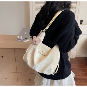 Cream hobo tote bag with a pink teddy bear charm shown worn on a model's shoulder