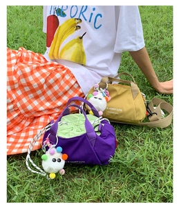 Detail of colorful canvas drawstring bag with pom-pom charm and striped shoulder strap