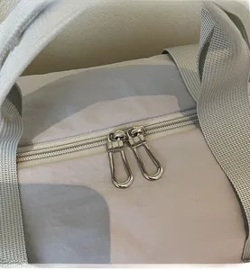 Détail de la fermeture à double glissière en métal et des poignées larges du sac en toile