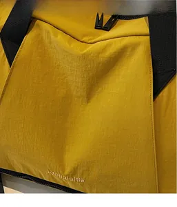 Detail of yellow nylon gym bag showing textured fabric and embroidered logo