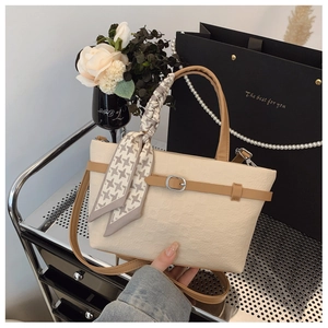 Gros plan d'un sac cabas crème en toile avec poignées en cuir marron et nœud en foulard