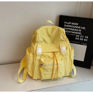 Détail d'un sac à dos en nylon jaune clair imperméable avec boucles blanches sur marbre
