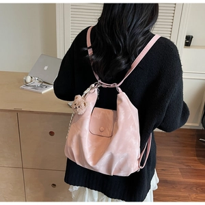 Detailed view of light pink nylon backpack with a cute brown teddy bear charm on the side