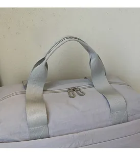 Détail du sac de voyage lilas montrant le tissu en nylon durable et les poignées robustes