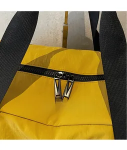 Close-up of dual black zippers and grey metal pullers on yellow polyester travel bag