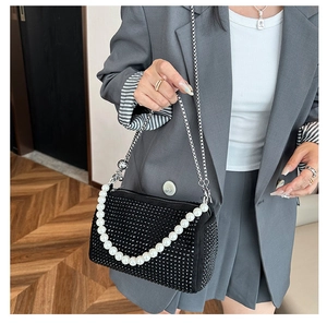 Close-up of black rhinestone Boston bag with large pearl handle and silver chain strap
