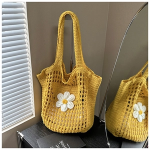 Gros plan d'un sac cabas tissé jaune orné de marguerites 3D blanches et texture crochet