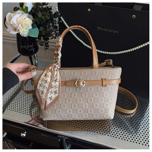 Détail du sac seau monogramme beige avec bordure en cuir marron et poignée en foulard