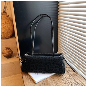 Detail of black leopard print suede shoulder bag with dual straps and drawstring accents