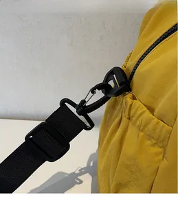 Detail of yellow nylon travel bag showing durable black plastic detachable hook and strap