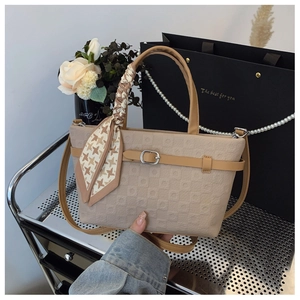 Détail du sac seau marron clair avec gaufrage carré, foulard en soie et boucle argentée