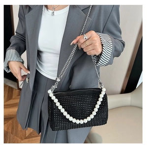 Detail of black rhinestone Boston bag with pearl handle and silver chain on a model