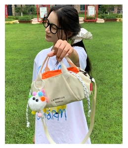 Close-up of minimalist canvas bag with orange drawstring lining and colorful charm