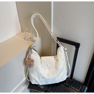 Detail shot of a stylish white large capacity hobo bag with a brown plush bear accessory