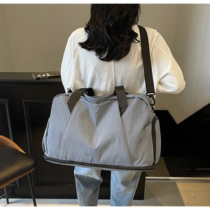 Light blue nylon gym bag shown from back view with adjustable shoulder straps and handle