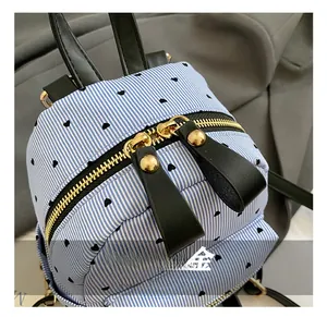 Close-up of gold zipper hardware and black leather puller on blue striped mini backpack