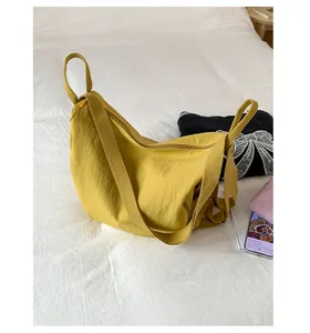 Detail view of ginger yellow nylon crescent crossbody bag with zipper and wide strap