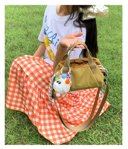 Detail of mustard yellow canvas bag with pleated texture and plush monster charm decoration