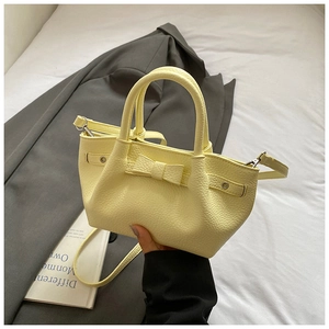 Dettaglio borsa a secchiello giallo brillante in pelle martellata con fiocco