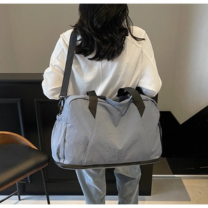 Rear view of a person carrying the light blue nylon travel bag with wet-dry separation
