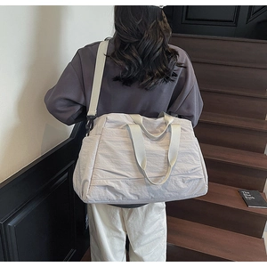 Vue arrière du modèle portant un grand sac cabas beige clair avec bandoulière