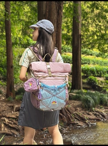 Detail of pink and blue hiking backpack with bungee cords and side mesh pocket in nature