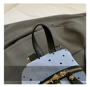 Top detail of striped canvas backpack with heart print, black leather handle and gold zippers