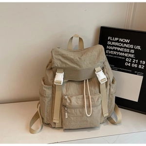 Détail du sac à dos en nylon kaki avec boucles blanches et poche frontale fonctionnelle
