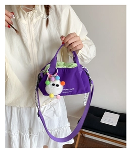Detail of purple canvas tote bag featuring green drawstring and cute plush pendant charm