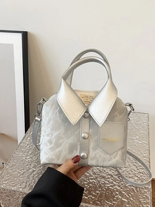 Unique silver shirt-shaped handbag with lapel and buttons, worn as a crossbody chain bag