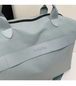 Detail der blauen Nylon-Reisetasche mit Ledergriffen und Metallreißverschluss