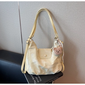 Detail of beige tie-dye nylon bag with plush bear charm and striped scarf accent