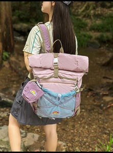 Detail of roll-top outdoor backpack with elastic X-cord and mini pouch in forest setting