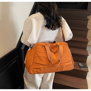 Grand sac de voyage orange en nylon porté par un mannequin avec bandoulière