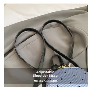 Close-up of adjustable black leather shoulder strap with gold hooks on striped mini backpack