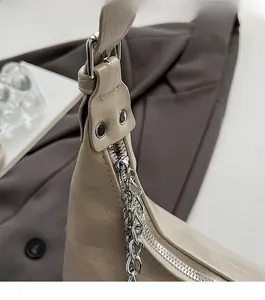 Detail der hellbeige genarbten Ledertasche mit silbernem Reißverschluss und Metallkette