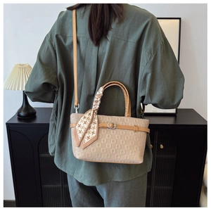 Détail du sac seau beige gaufré avec lanières en cuir marron et foulard en soie à motifs