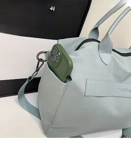 Praktisches Seitenfach einer hellblauen Nylon-Tragetasche mit einem Smartphone
