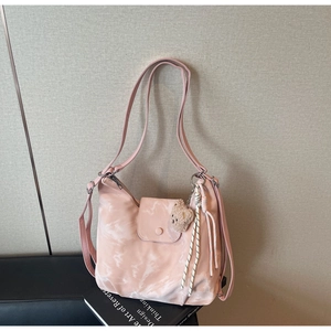 Detail of pink tie-dye shoulder bag with plush bear charm and woven tassel rope