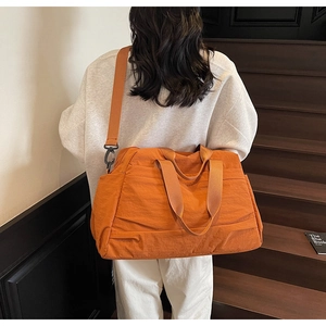 Vue arrière d'un mannequin portant un grand sac de voyage en nylon orange dans un escalier