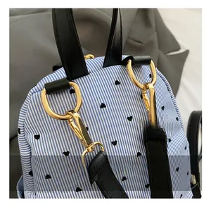 Detail of blue and white striped backpack with heart prints and gold metal hardware
