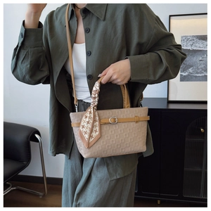Détail d'un sac seau kaki texturé avec foulard en soie enroulé et boucle argentée chic