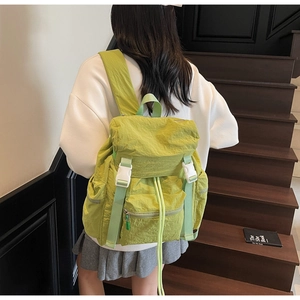 Voyageur avec sac à dos en nylon vert imperméable et cordon sur escalier en bois