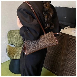 Chic leopard print underarm bag with slim brown strap worn in a stylish setting