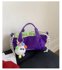 Detail of purple canvas tote bag with contrast green lining and colorful plush pompom