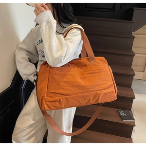 Détail macro du grand sac cabas en nylon orange avec bandoulière et poignées robustes