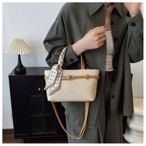 Détail du sac seau crème texturé avec anses brunes et foulard en soie pied-de-poule