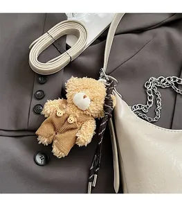 Nahaufnahme eines Teddybär-Anhängers mit brauner Cordhose an einer beigen Handtasche