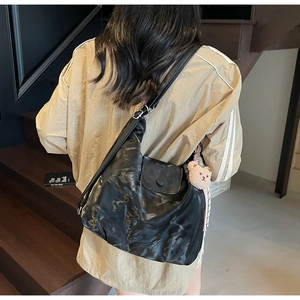 Hobo shoulder bag in black textured leather featuring a brown plush bear keychain
