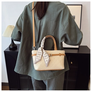Détail du sac seau crème avec foulard en soie à motif et bandoulière en cuir réglable
